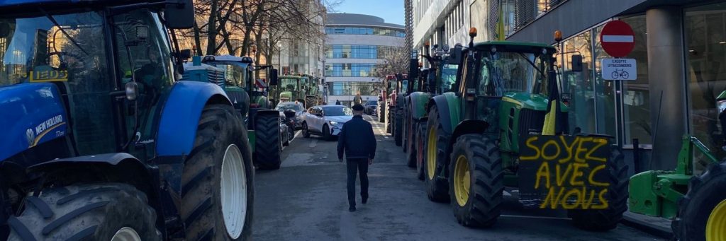 Tractors parked in the strees of Brussels, on one of them there is a placard that says in French "Be with us"