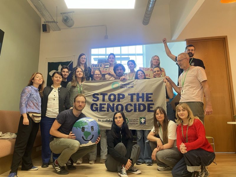 Participants of the Economic Justice meeting holding a banner saying "stop genocide".